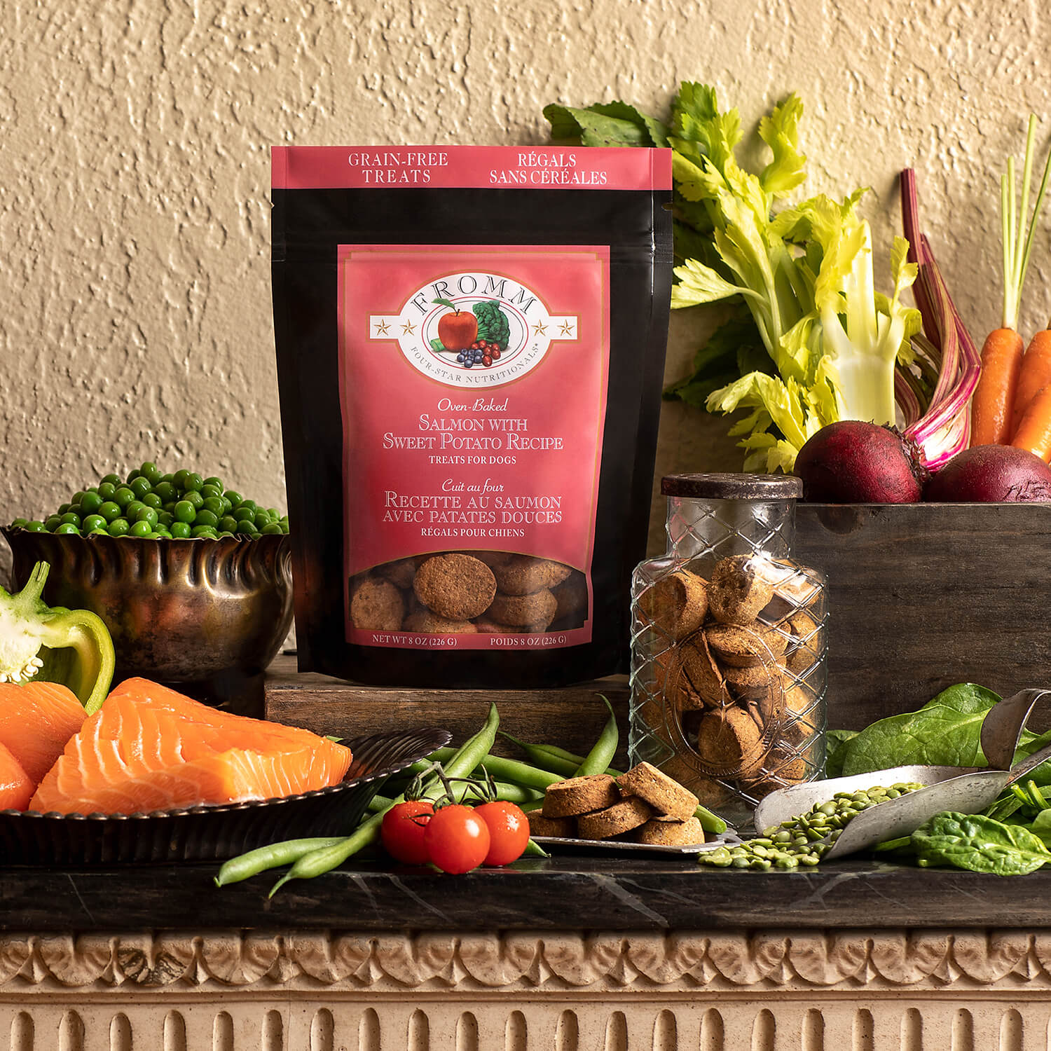 Bag of Fromm dog food on a table with fresh vegetables and treats.